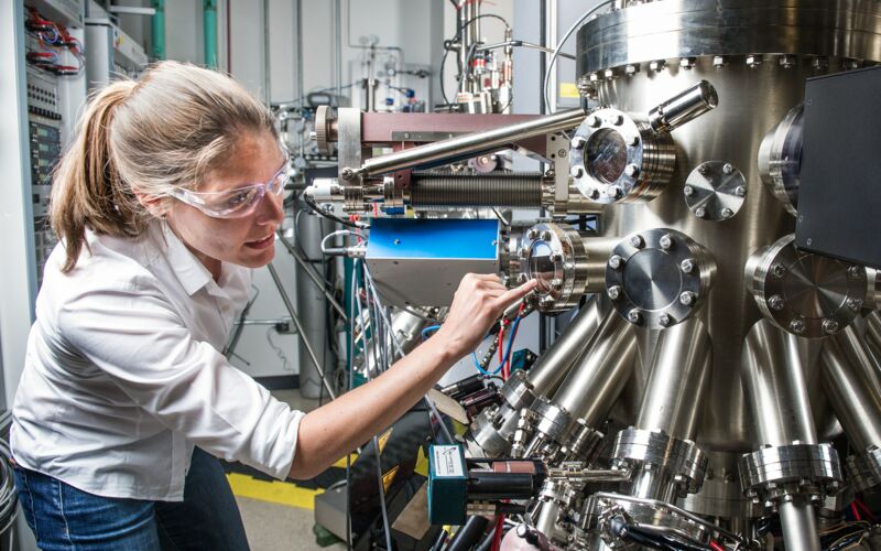 Woman with safety glasses examines an industrial machine