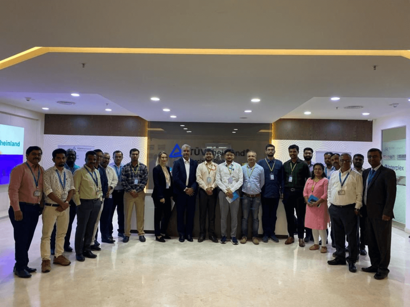 Viele Personen von der Delegation und TÜV Rheinland stehen in einer Empfangshalle.