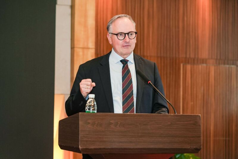 Ein Mann im Anzug steht vor einem Rednerpult.